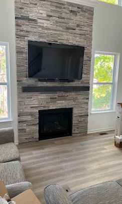 TV mounted on a tall stacked-stone fireplace wall
